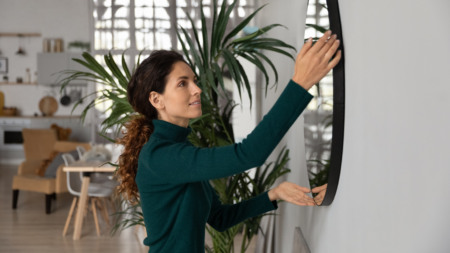 Mulher pendura espelho em apartamento decorado Mulher pendura espelho em apartamento decorado