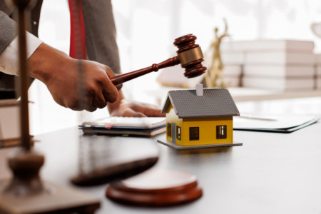 Homem bate martelo sobre mesa. Há uma miniatura de casa sobre a mesa Homem bate martelo sobre mesa. Há uma miniatura de casa sobre a mesa