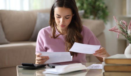 Mulher analisa papel em uma mesa, com calculadora ao lado, remetendo a pagamento de contas, boletos, impostos (IPTU) etc. Foto: AntonioGuillem / iStock Mulher analisa papel em uma mesa, com calculadora ao lado, remetendo a pagamento de contas, boletos, impostos (IPTU) etc. Foto: AntonioGuillem / iStock