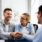 Casal cumprimenta gerente do outro lado da mesa, em uma transação de negócios, como, por exemplo, financiamento imobiliário. Casal cumprimenta gerente do outro lado da mesa, em uma transação de negócios, como, por exemplo, financiamento imobiliário.