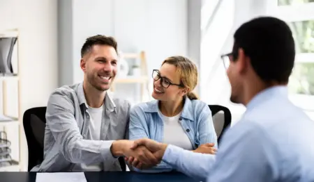 Casal cumprimenta gerente do outro lado da mesa, em uma transação de negócios, como, por exemplo, financiamento imobiliário. Casal cumprimenta gerente do outro lado da mesa, em uma transação de negócios, como, por exemplo, financiamento imobiliário.