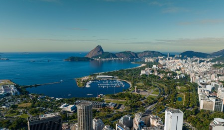 Vista aérea elevada da Marina da Glória, do Parque do Flamengo e do horizonte urbano ao redor, com o Pão de Açúcar e a Baía de Guanabara ao fundo. Barcos estão atracados na marina e avenidas costeiras são visíveis. Perspectiva de vista aérea elevada do Rio de Janeiro. Vista aérea elevada da Marina da Glória, do Parque do Flamengo e do horizonte urbano ao redor, com o Pão de Açúcar e a Baía de Guanabara ao fundo. Barcos estão atracados na marina e avenidas costeiras são visíveis. Perspectiva de vista aérea elevada do Rio de Janeiro.