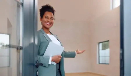 Corretora de imóveis dando as boas vindas a alguém na porta de um imóvel. Corretora de imóveis dando as boas vindas a alguém na porta de um imóvel.