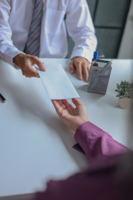 Mão entregando envelope com contrato para outra pessoa em escritório Mão entregando envelope com contrato para outra pessoa em escritório