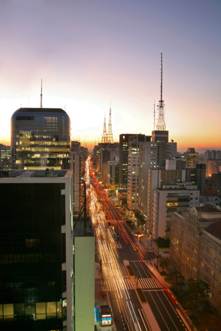 Vista aérea da Avenida Paulista ao entardecer com rastros de luz dos carros