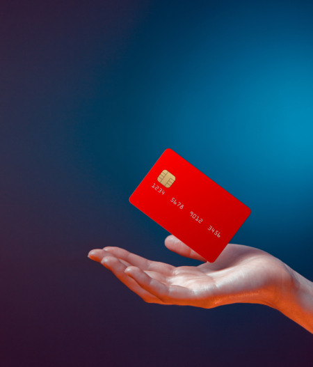Cartão de crédito vermelho flutuando sobre a mão de uma pessoa, representando garantia financeira Cartão de crédito vermelho flutuando sobre a mão de uma pessoa, representando garantia financeira