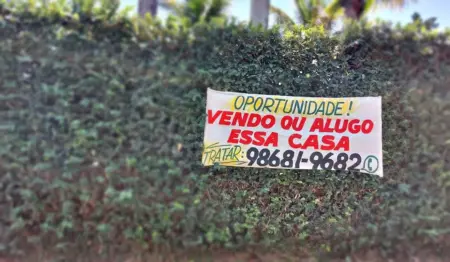Faixa sobre muro diz: "Oportunidade - vendo ou alugo esta casa" Faixa sobre muro diz: "Oportunidade - vendo ou alugo esta casa"