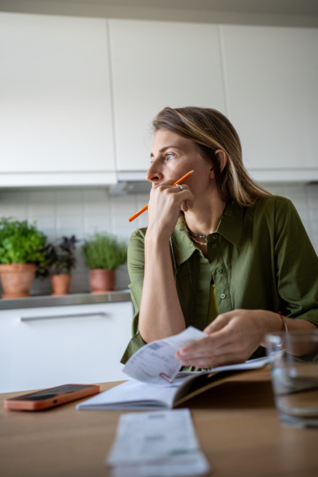 Mulher pensativa revisando contas e orçamento na cozinha