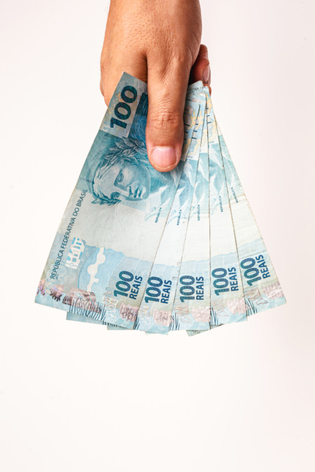 Mão segurando notas de 100 reais em leque