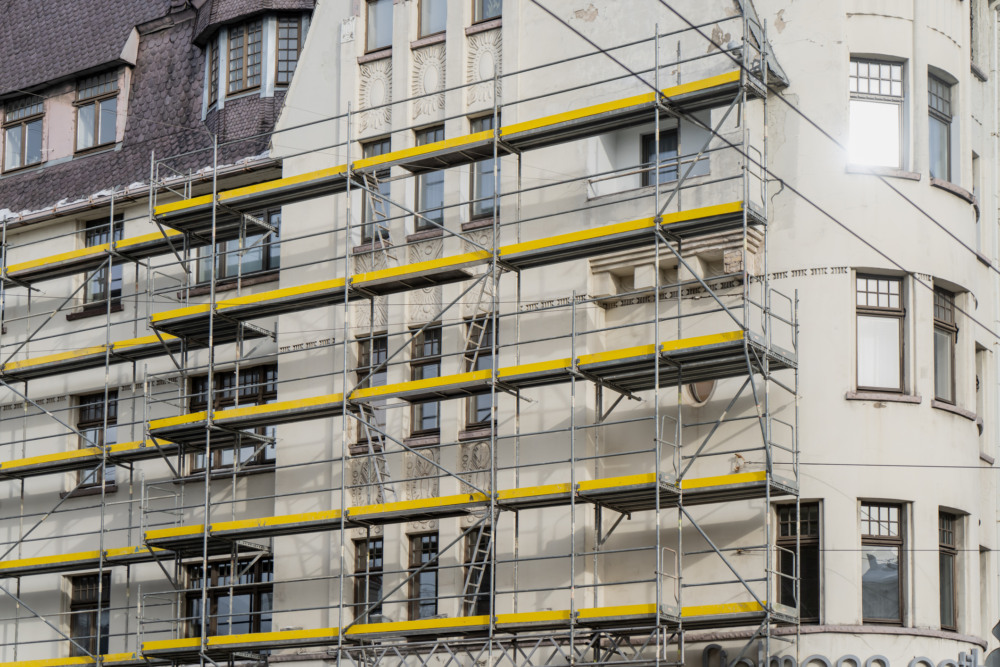 Andaimes amarelos e metálicos cobrindo a fachada de um edifício antigo em processo de retrofit/restauração Andaimes amarelos e metálicos cobrindo a fachada de um edifício antigo em processo de retrofit/restauração
