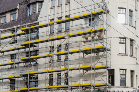 Andaimes amarelos e metálicos cobrindo a fachada de um edifício antigo em processo de retrofit/restauração Andaimes amarelos e metálicos cobrindo a fachada de um edifício antigo em processo de retrofit/restauração