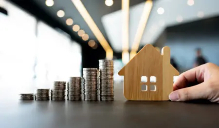 Monte de moedas empilhadas ao lado de uma casinha de madeira em miniatura, remetendo à ideia de financiamento imobiliário, como o SFI. Monte de moedas empilhadas ao lado de uma casinha de madeira em miniatura, remetendo à ideia de financiamento imobiliário, como o SFI.